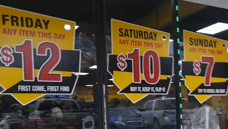 Price signs on windows outside of a  liquidation bin store in north Raleigh. The signs read Friday $12, Saturday $10, and Sunday $7.
